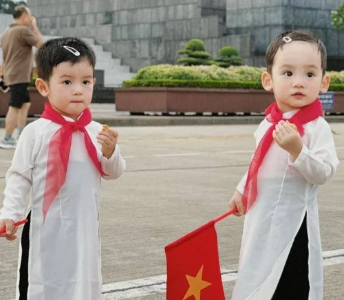 Hai bé mặc áo dài trắng cầm cờ Việt Nam 30/4