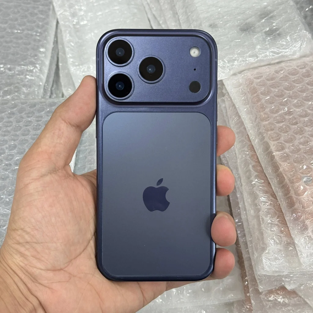 Tay cầm chiếc iPhone 17 Pro Max màu xanh đen trên nền xốp chống sốc